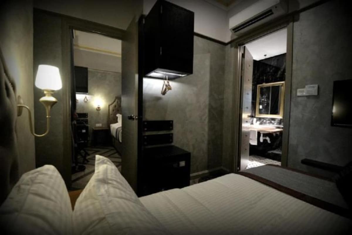 Une chambre d’hôtel comprenant un lit, un bureau, une chaise, une lampe, une armoire et un miroir.