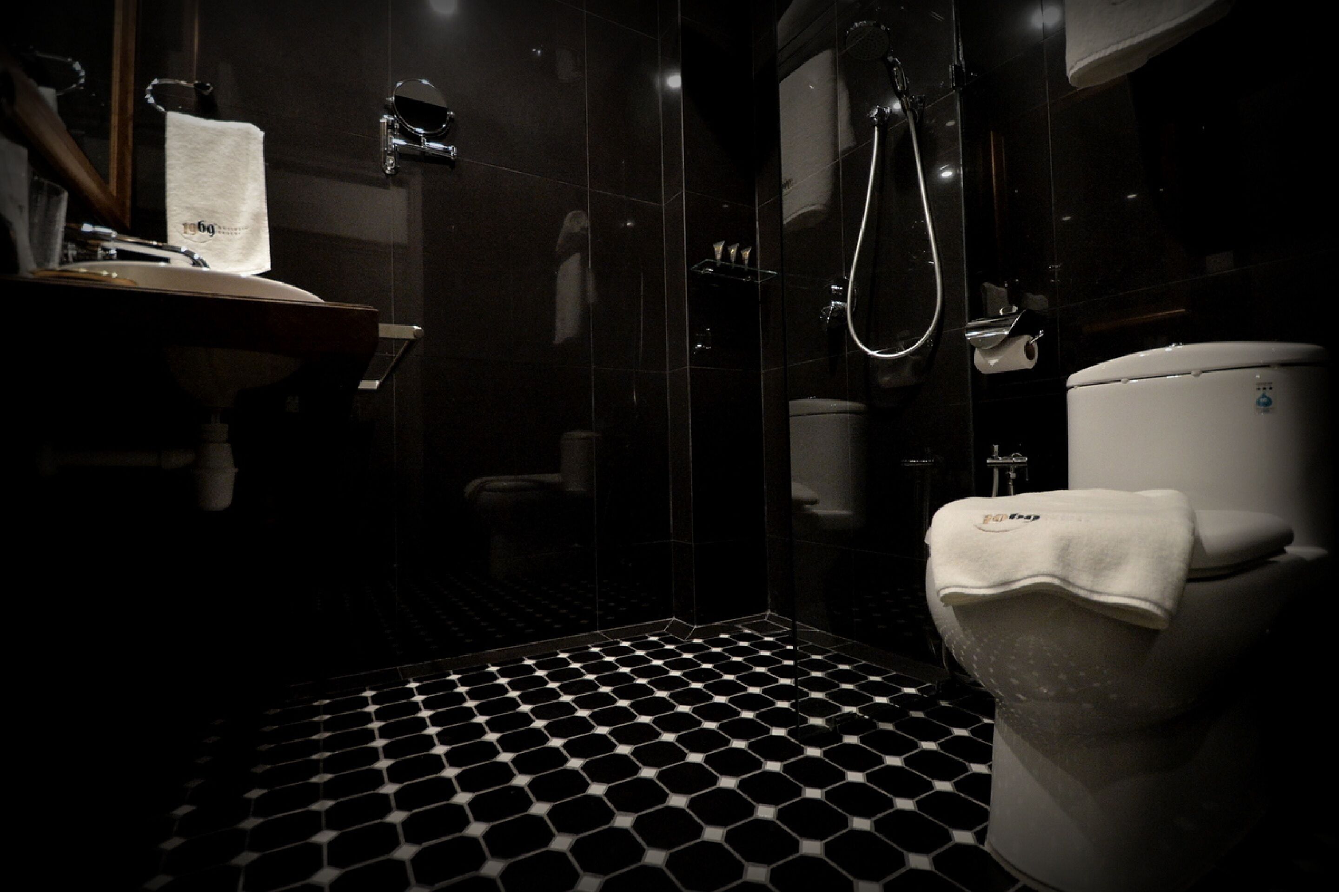Une salle de bain avec un carrelage noir et blanc à motifs de damier, des toilettes blanches et une douche à parois de verre.