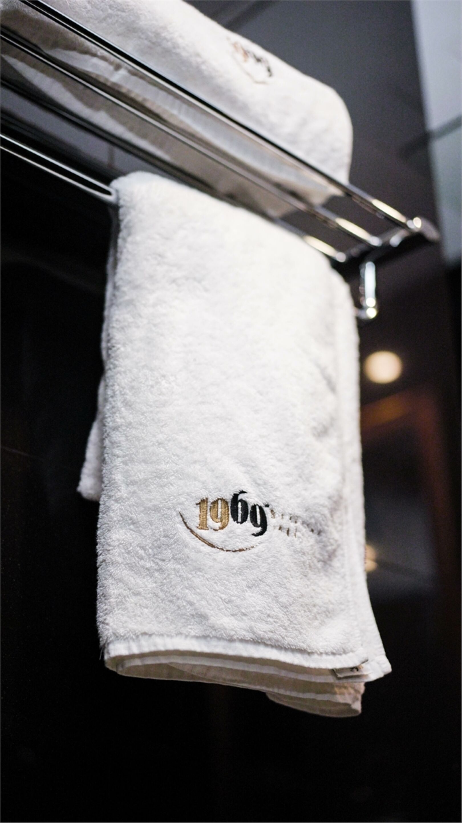 A white towel hanging on a metal rack with a visible weight marking of 196g.