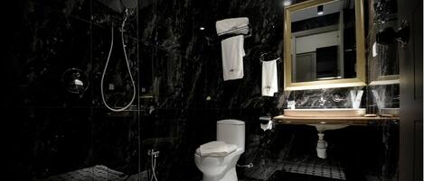 Un bany modern amb dutxa de vidre, vàter i un lavabo amb mirall a sobre.