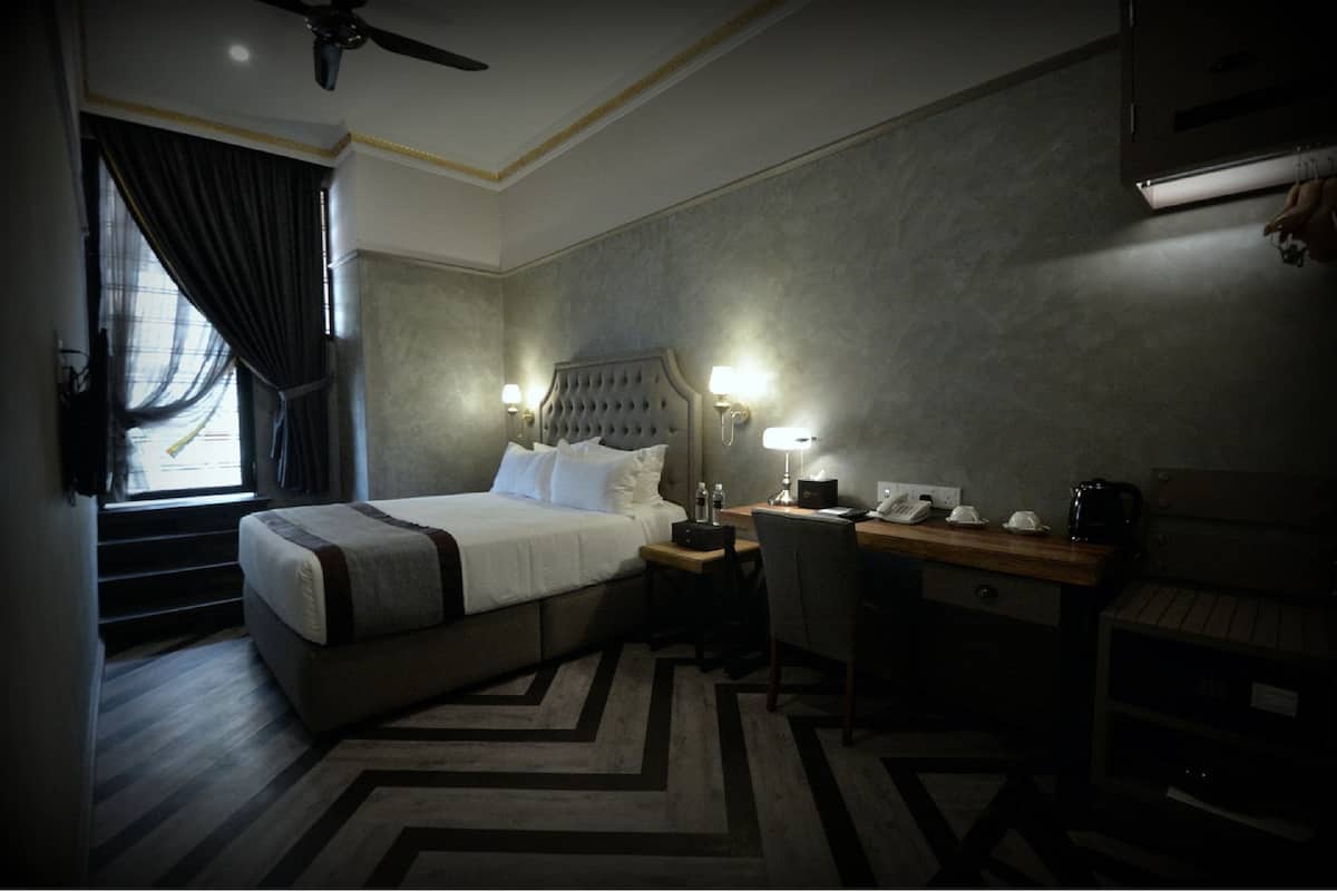 Ein Hotelzimmer mit Bett, Schreibtisch, Stuhl und einer Treppe, die in einen Außenbereich führt.