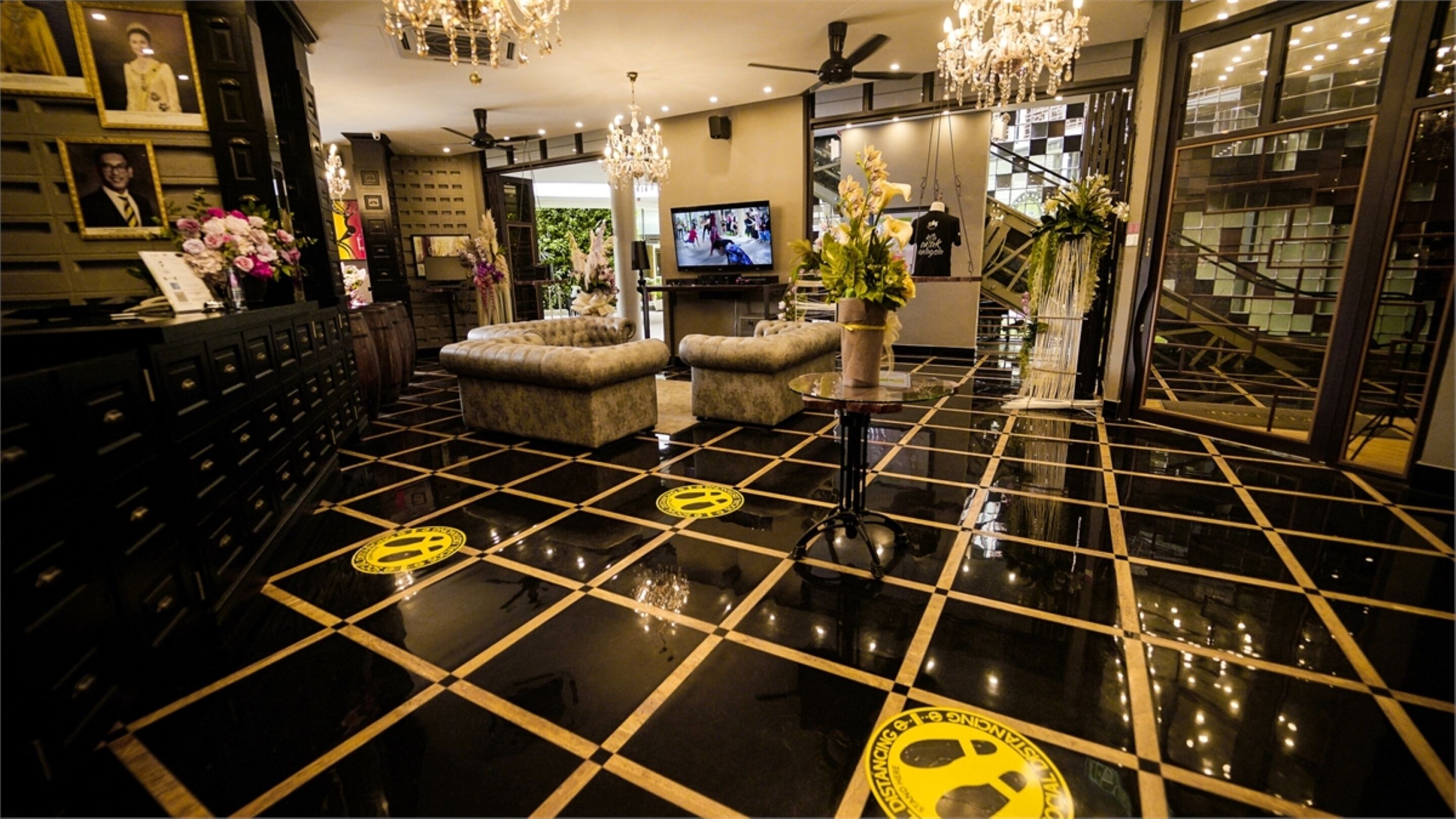A lobby with a checkered floor, a television, and a reception desk with framed photos.