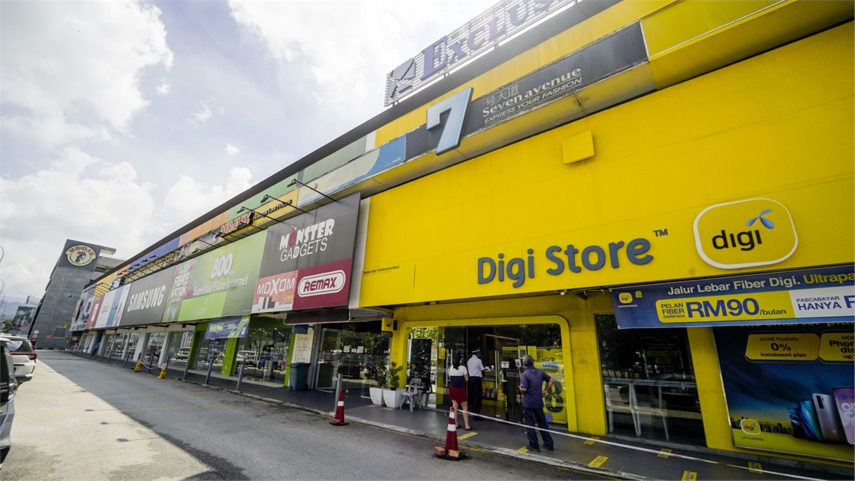 A multi-story commercial building with various retail stores, including a prominent yellow 'Digi Store' sign.