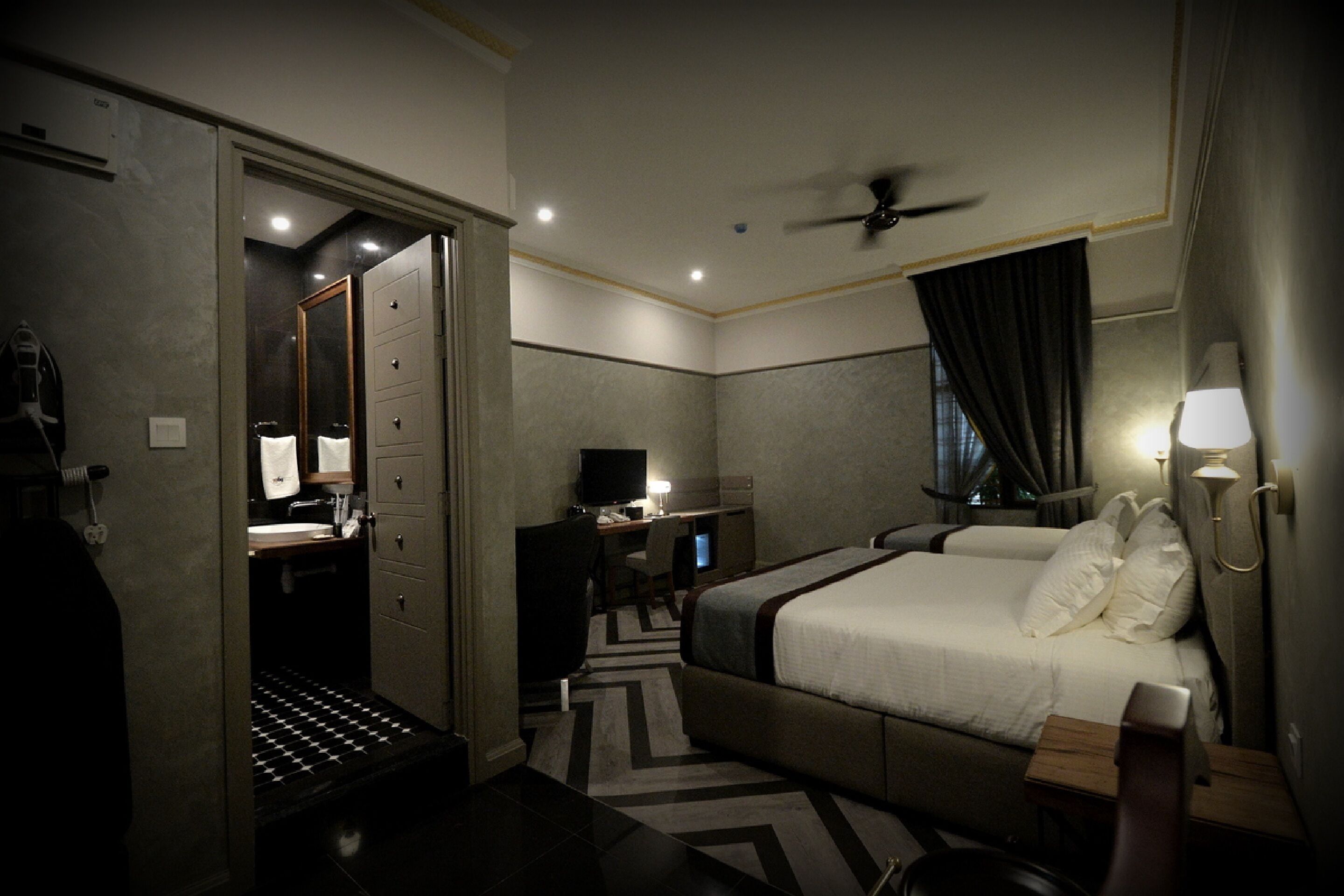 Quarto de hotel com cama, escrivaninha e espelho.