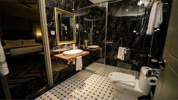 Et moderne badeværelse med en brusekabine i glas, en trækommode, en hvid vask og et toilet.