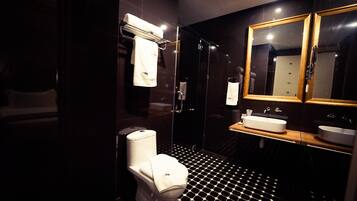 Un baño moderno con piso de baldosas blanco y negro, un inodoro blanco, un lavamanos con encimera de madera y un espejo con marco de madera.