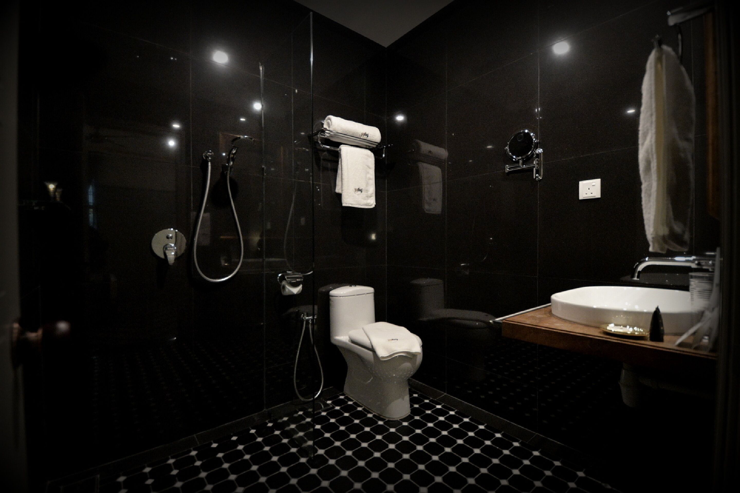 A modern bathroom with a black and white checkered floor, a white toilet, a sink, and a glass-enclosed shower area.