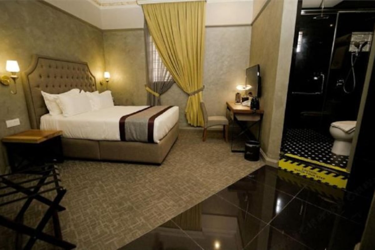 Une chambre d’hôtel avec un grand lit, un bureau avec une chaise, une télévision et un espace douche.