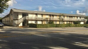 A two-story motel with a balcony on the second floor, a parking lot in front, and a clear sky. - Miami Airport Apartment Inn (Miami)