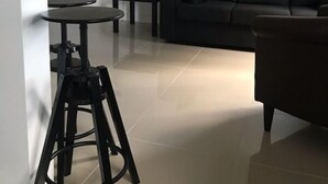 A modern living room with a dark sofa, a small coffee table, and a kitchen area with a bar stool. - Miami Airport Apartment Inn (Miami)
