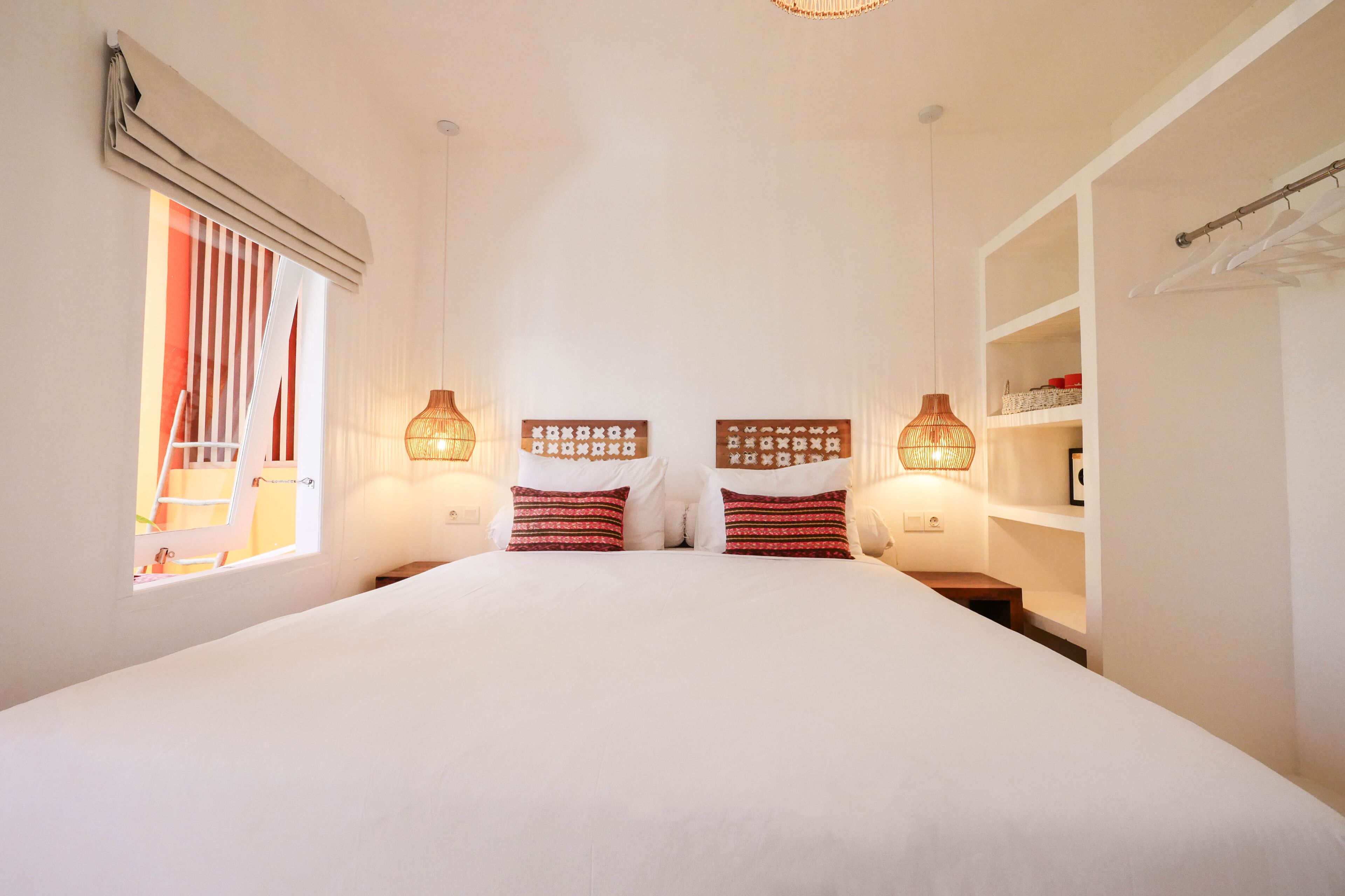 A bedroom with a large bed, two bedside tables, a wardrobe, and a window with curtains.