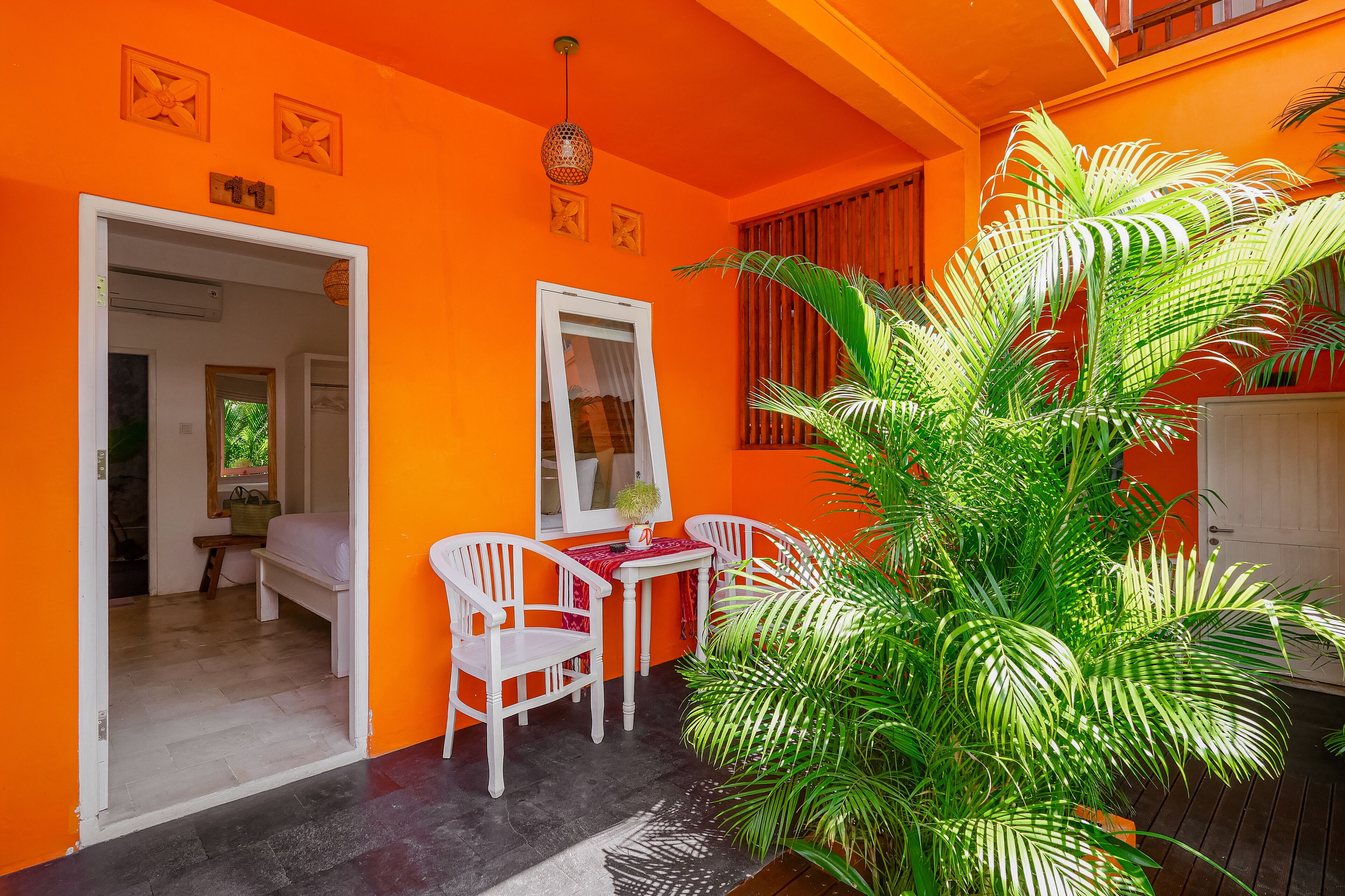 Una habitación con paredes anaranjadas, muebles blancos y una planta grande en maceta.