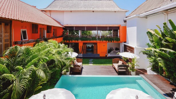 A courtyard with a swimming pool, wooden deck, and outdoor seating.