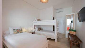Un dormitorio con una litera, una cama individual, un banco de madera, un televisor montado en la pared y una lámpara de techo tejida.