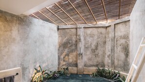 A modern bathroom with a concrete floor, a shower area, and a ceiling with a wooden slat design.