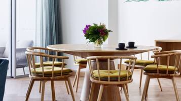 Uma mesa redonda de madeira com quatro cadeiras, cada uma com almofada. Um vaso com flores está sobre a mesa.