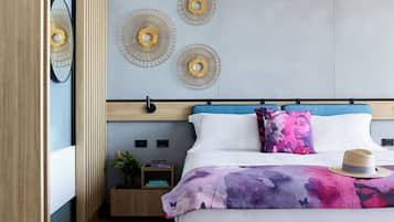 A modern bedroom with a bed, decorative wall art, a bedside table with a plant, and a nightstand.