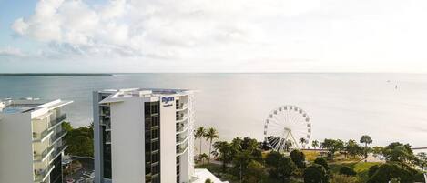 A modern hotel with a Ferris wheel in the background, overlooking a calm sea.