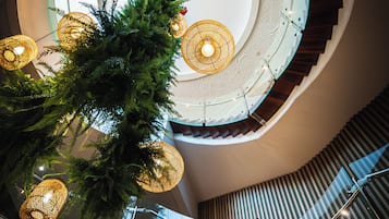 A modern interior with a spiral staircase, glass railings, and decorative lighting fixtures.