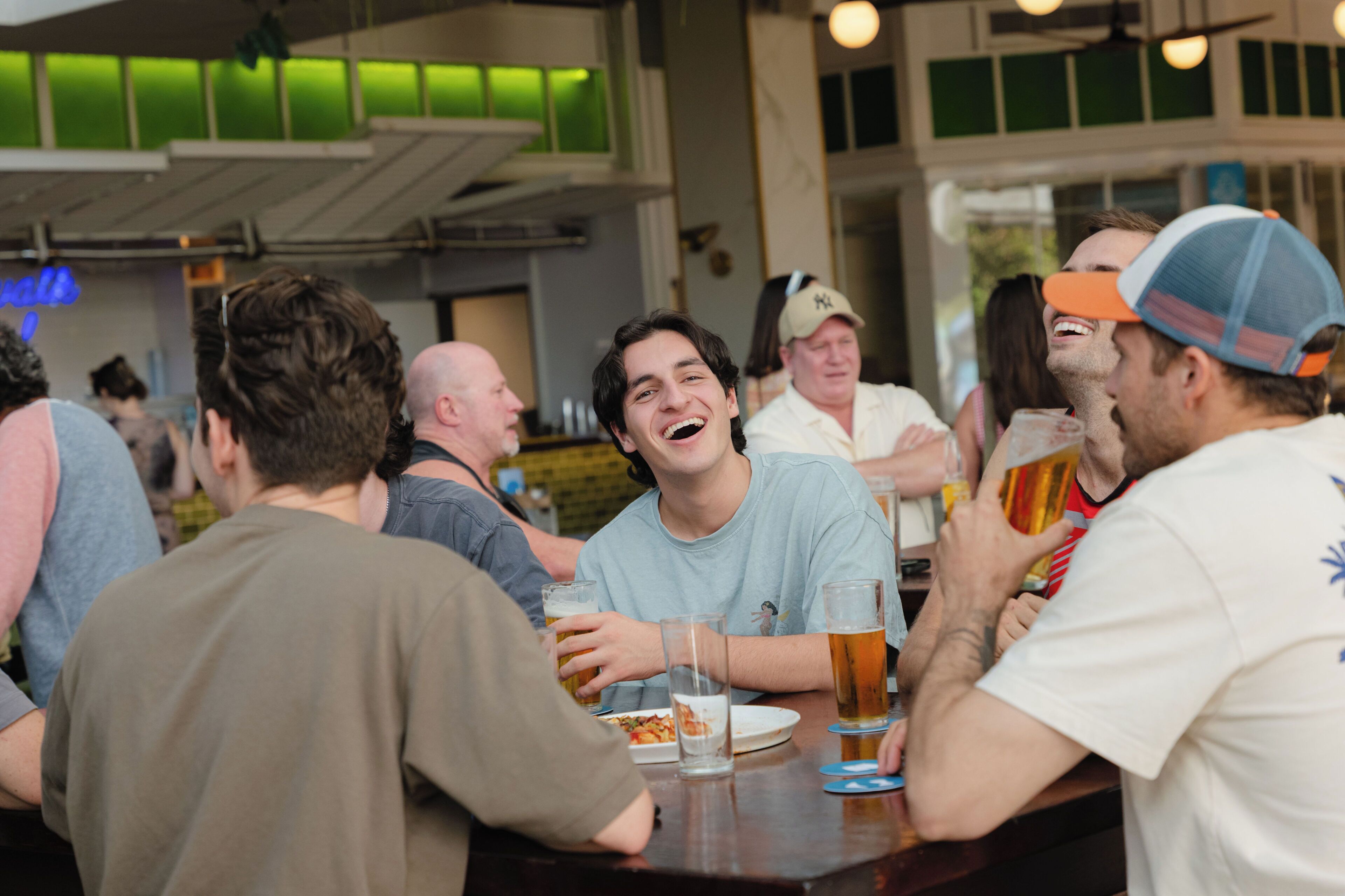 A group of people seated at a table in a restaurant with a view of a building with large windows.