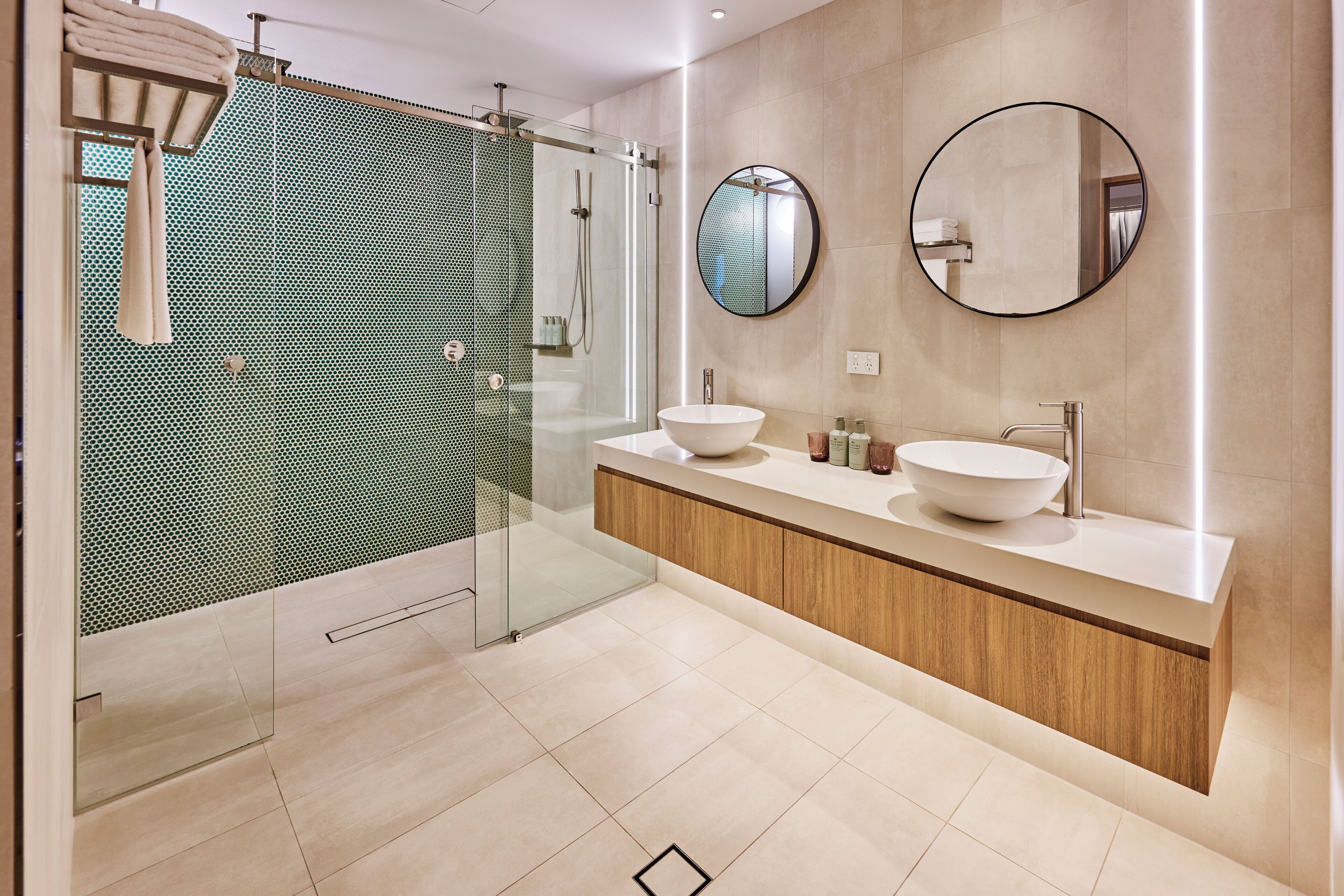 A modern bathroom with a glass shower enclosure, two sinks, and a large mirror.