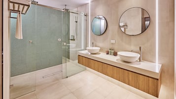 A modern bathroom with a glass shower enclosure, two sinks, and a large mirror.