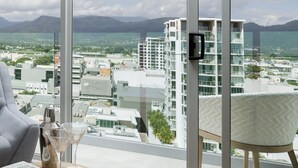 A modern room with a large window overlooking a cityscape and mountains. - Crystalbrook Flynn (Cairns)