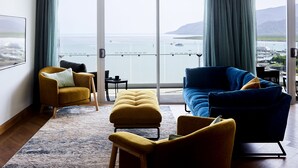A modern living room with a large window, a sofa, a chair, and a small table. - Crystalbrook Flynn (Cairns)