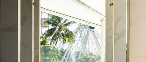 A pool area with a view of a palm tree and a Ferris wheel.
