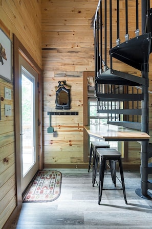 A wooden interior with a staircase, a table, and chairs.
