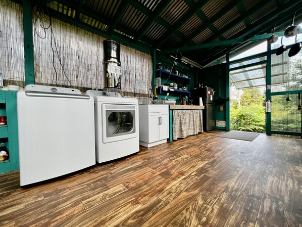 Una cocina con lavadora, suelo de madera y vistas al exterior con zonas verdes.
