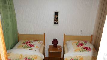 Ein Zimmer mit zwei Betten, jeweils mit floralem Bettzeug, einem kleinen Nachttisch mit Lampe und einem Bild an der Wand.