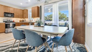 Una cocina moderna con armarios de madera, una isla grande con sillas, un microondas y un comedor con vistas.
