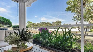 Un área de estar al aire libre cubierta con una mesa de madera, plantas en macetas y vistas del paisaje circundante.