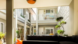 A spacious atrium with a black leather sofa, a hanging light fixture, and a view of the upper floor. - Mantra Gili (Gili Trawangan)