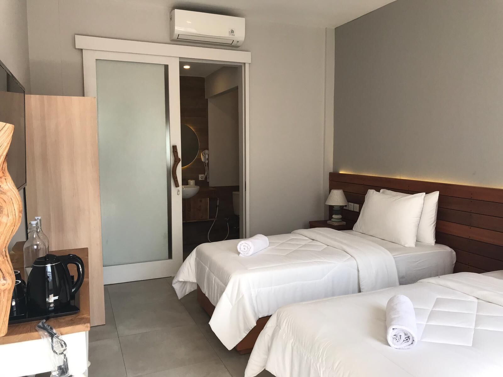 Camera d'albergo con due letti, una macchina per il caffè, un lavandino e un condizionatore d'aria.