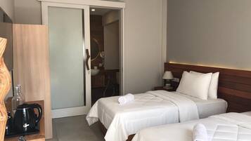 Camera d'albergo con due letti, una macchina per il caffè, un lavandino e un condizionatore d'aria.