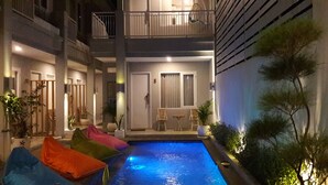 A two-story building with a swimming pool, outdoor seating, and potted plants. - Mantra Gili (Gili Trawangan)