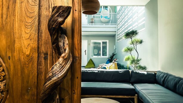A modern interior with a wooden accent wall, a blue sofa, and a small round table. - Mantra Gili (Gili Trawangan)