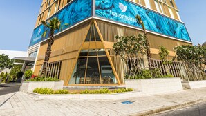 A tall hotel with a modern design, featuring a prominent blue advertisement on the facade. - Fusion Suites Vung Tau (Ho Chi Minh City)