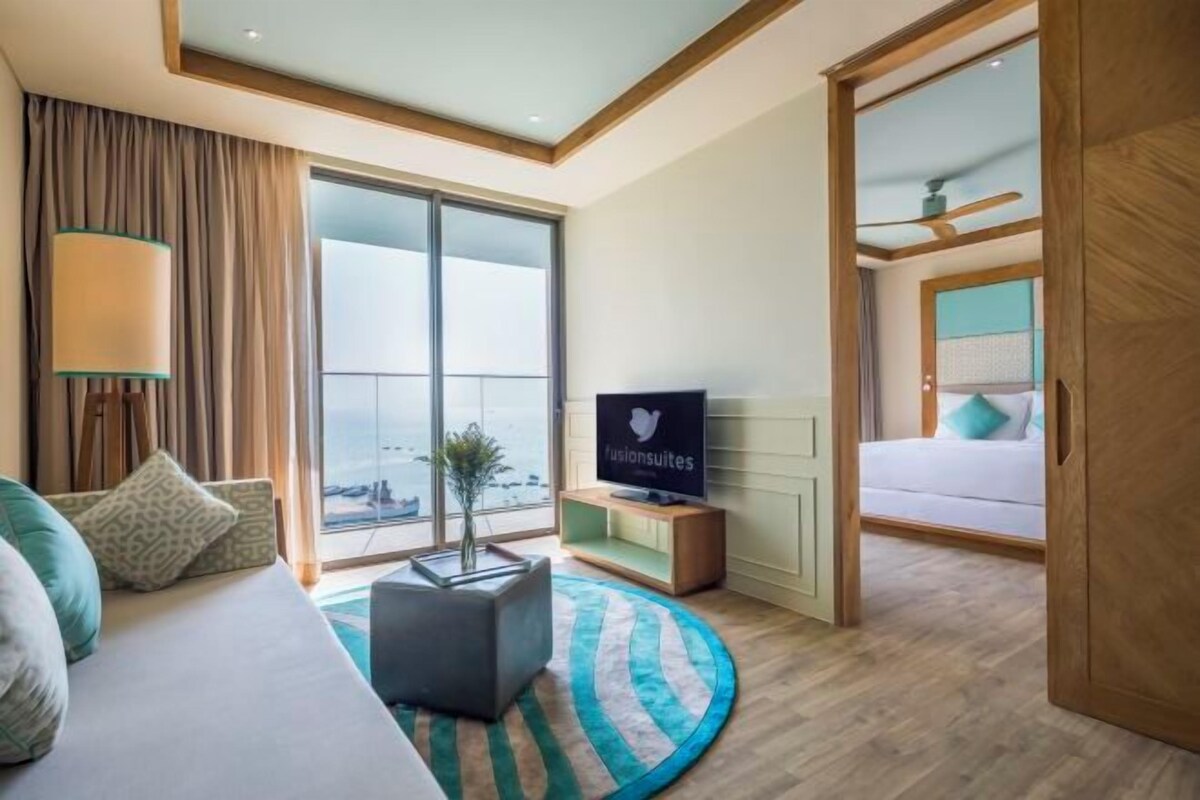 A hotel room with a bed, a TV, a desk, a window with a view, and a sliding door to another room.