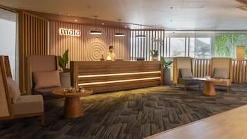 A reception area with a wooden reception desk, two receptionists, and seating arrangements including sofas and chairs.
