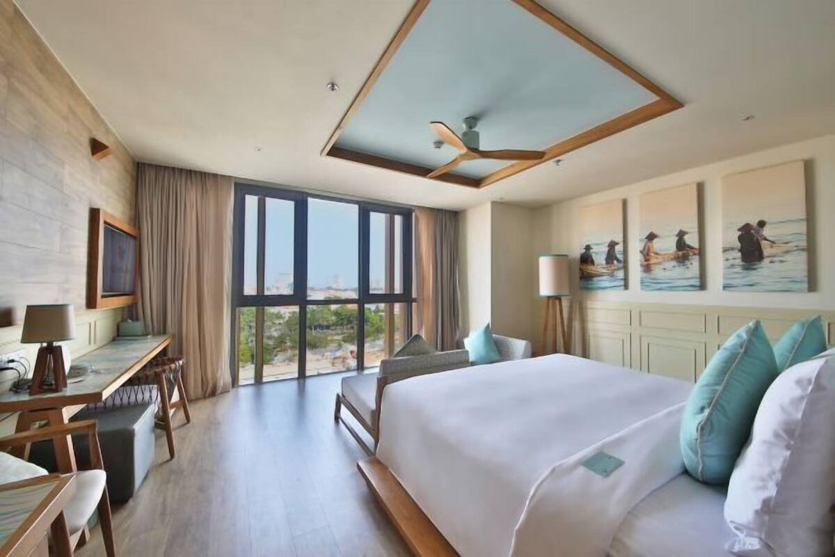 Habitación de hotel con una cama grande, un escritorio y vistas al exterior.