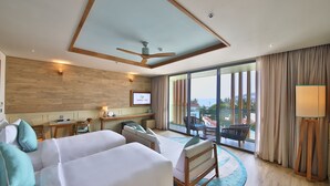 A hotel room with two beds, a ceiling fan, a TV, a balcony with a view, and a desk with a chair. - Fusion Suites Vung Tau (Ho Chi Minh City)