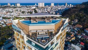 A high-rise hotel with a rooftop pool and lounge area, surrounded by a cityscape and a view of the sea. - Fusion Suites Vung Tau (Ho Chi Minh City)