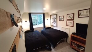 Une chambre avec deux lits, une télévision et des tableaux encadrés au mur.