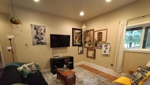Un salon avec un canapé, une table basse, un téléviseur et des tableaux encadrés accrochés au mur.