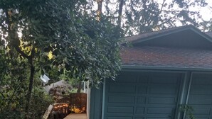 A garage with a green door, a wooden deck, and a car parked in front.
