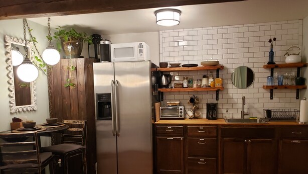 A kitchen with a refrigerator, microwave, coffee maker, and wooden cabinets.
