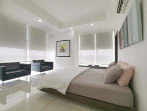 Une chambre moderne avec un grand lit, un canapé et une fenêtre équipée de stores.